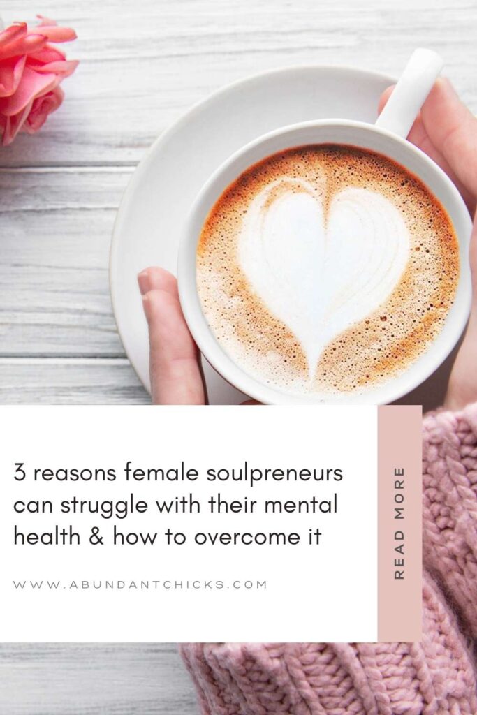 a female soulpreneur with a pink woollen jumper is holding a cup of coffee in both her hands with a heart made out of foam in it. We only see her hands, not her face. She is going through a rough time with her mental health and is trying to overcome it